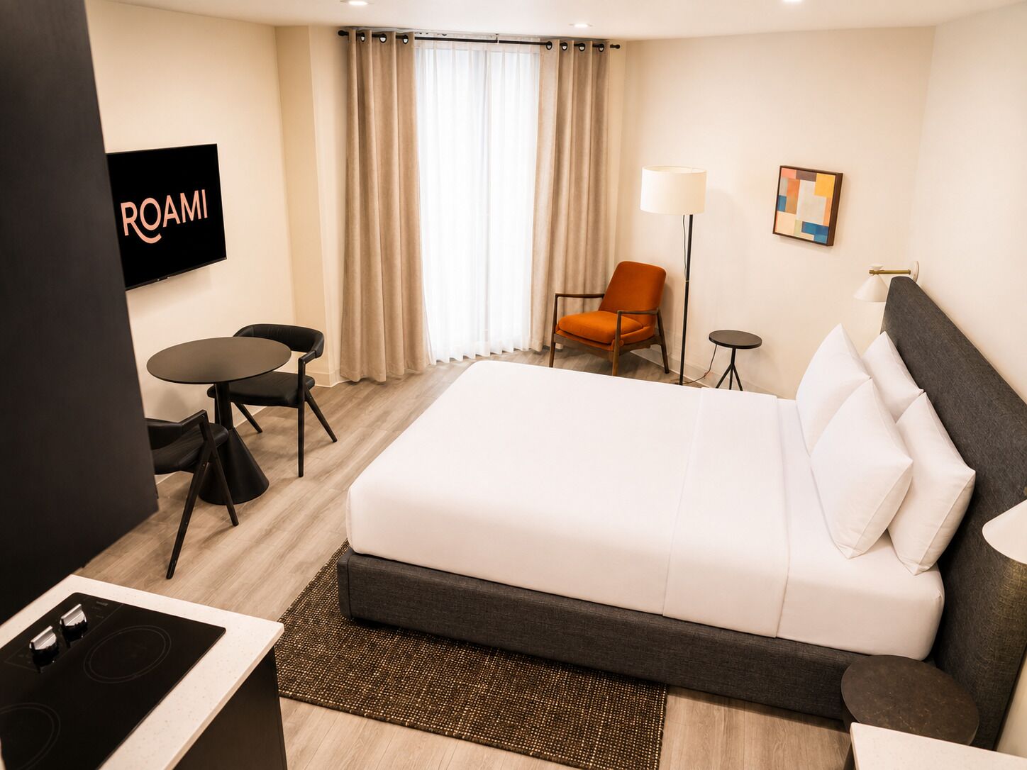 Una habitación de hotel con cama, escritorio, silla, televisión y lámpara.