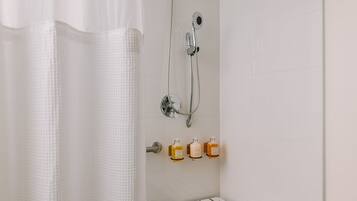 A bathroom with a shower, a towel rack, and a shelf with toiletries.