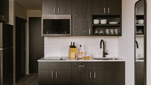 A modern kitchen with dark wood cabinets, a stainless steel microwave, and a white countertop. - Roami at The Fitz (St. Paul)