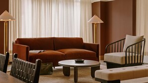 A modern living room with a brown sofa, a round coffee table, and a chair with a cushioned backrest. - Roami at The Fitz (St. Paul)