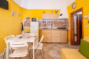 Una cucina compatta con zona pranzo, frigorifero, forno a microonde e piano cottura.