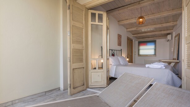 Une chambre avec deux lits, un plafond en bois et une grande fenêtre.