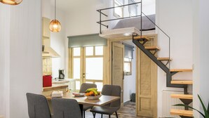 Une cuisine moderne avec un coin repas, un escalier en bois et de grandes fenêtres.