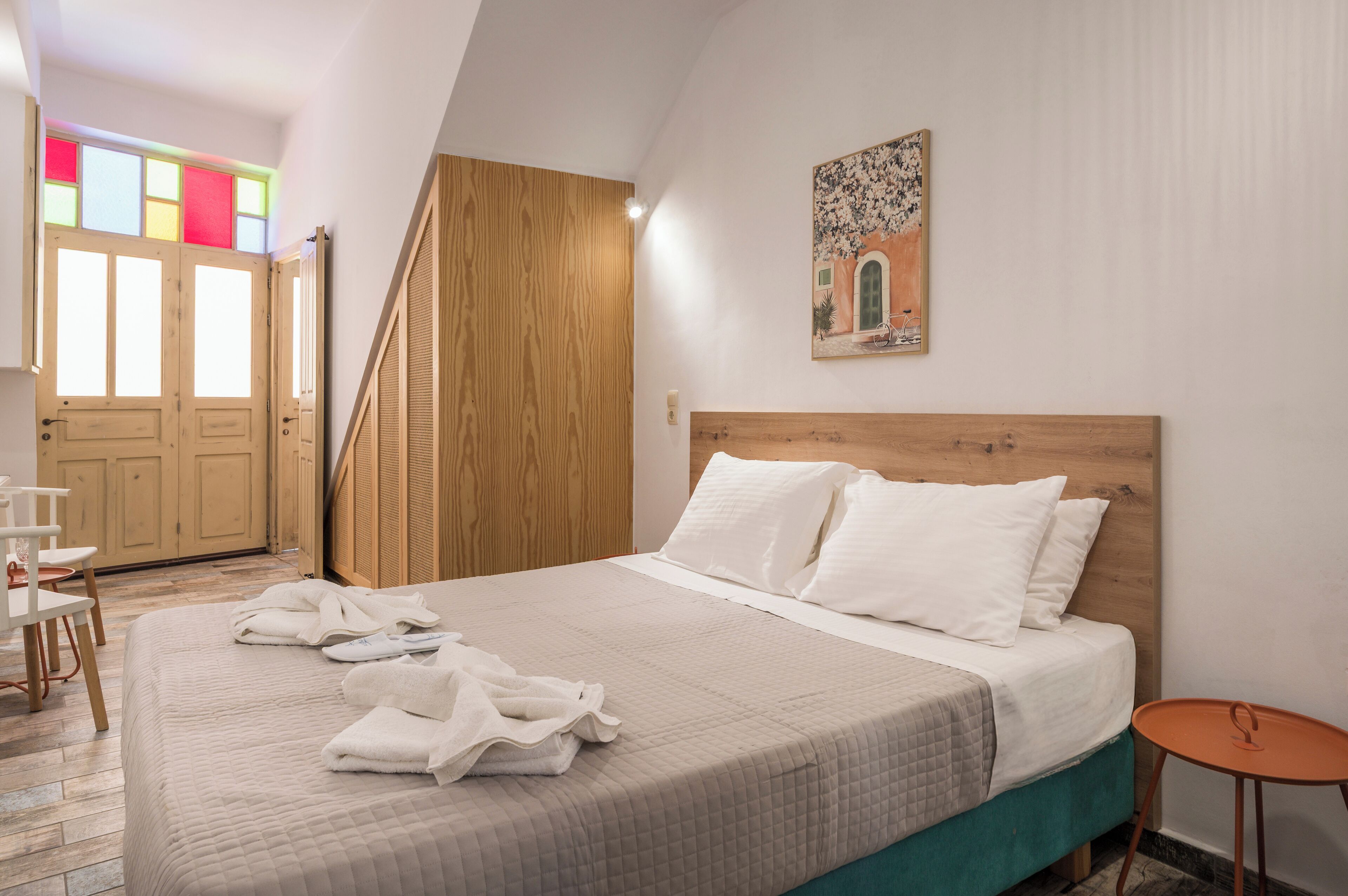 Une chambre à coucher avec un lit, une tête de lit en bois, une petite table et un tableau accroché au mur.