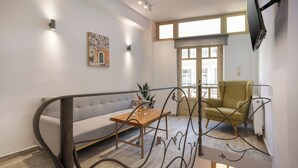 Un salon moderne avec un canapé, une table en bois, un fauteuil vert et un téléviseur fixé au mur.