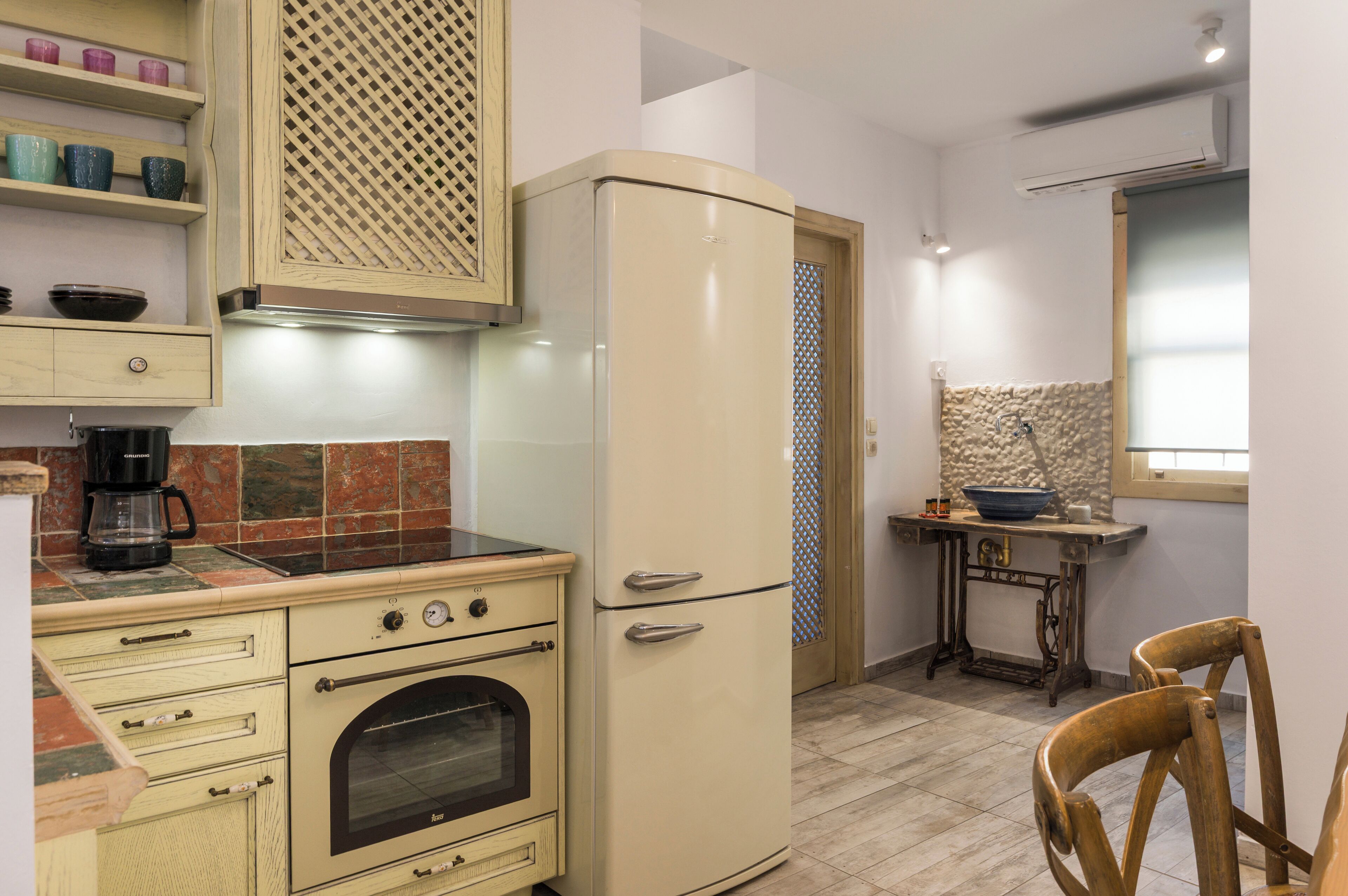 A kitchen with a vintage refrigerator, an oven, and a coffee maker.