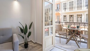 Un balcon avec une table et des chaises, un pot de fleurs et une vue sur un immeuble doté de balcons.