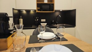 Une cuisine moderne avec un plan de travail noir, un four à micro-ondes et un évier. On y trouve une table à manger mise avec des assiettes, des verres et des couverts.