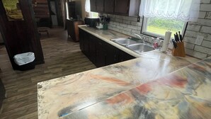 Une cuisine avec des meubles en bois foncé, un plan de travail en marbre et une fenêtre donnant sur un paysage verdoyant.