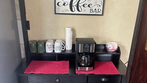 Un espace de travail compact équipé d’une machine à café, de tasses et d’un panneau indiquant l’emplacement du coin café.