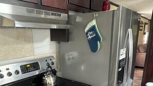 Une cuisine équipée d’un réfrigérateur en acier inoxydable, d’une cuisinière et de meubles de rangement en bois.