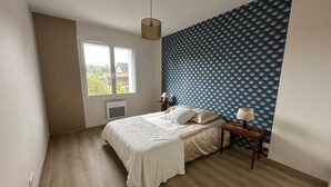A bedroom with a bed, a nightstand, a lamp, a window, and a wall with a fan pattern. - L'ECRIN DE JOSELIA, 60m2 renovated family home in Périgord Vert (QUINSAC)