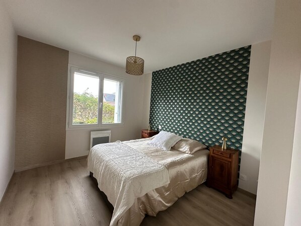Une chambre à coucher avec un lit, une fenêtre, un radiateur et un mur décoré de motifs.