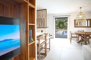 Ein modernes Interieur mit Fernseher, Holzmöbeln, einem Essbereich und Blick ins Freie.