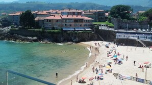 A beach with clear waters, a sandy shore, and buildings in the background. - Apartment for 2 in the center of Nueva (Nueva de Llanes)