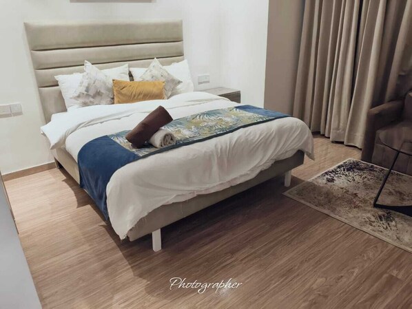 A modern bedroom with a bed, a nightstand, and a chair. - Aipl Joy street  (Gurugram)