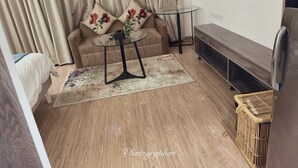 A compact living space with a sofa, a small round table, a TV mounted on the wall, and a wooden floor. - Aipl Joy street  (Gurugram)