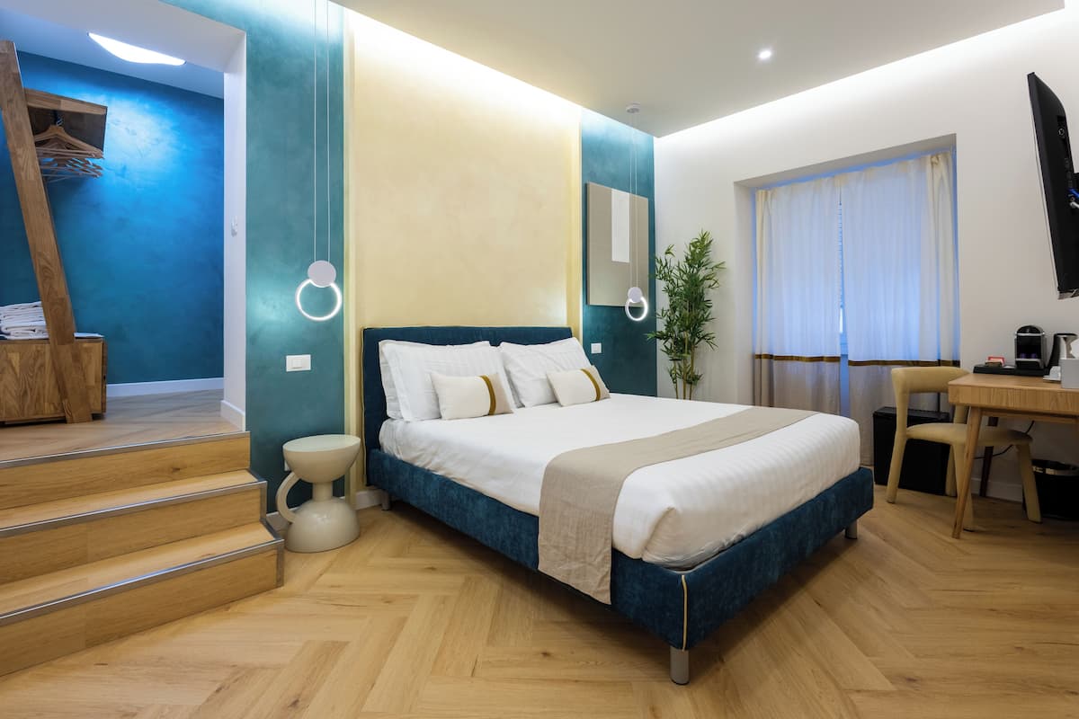 A modern bedroom with a bed, a desk, and a chair. There are stairs leading to a loft area.