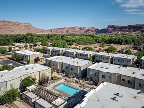 A modern apartment complex with a rooftop pool, surrounded by greenery and mountains. - Entrada 631 & 635 | Pet Friendly I Pool & Hot Tub (Moab)