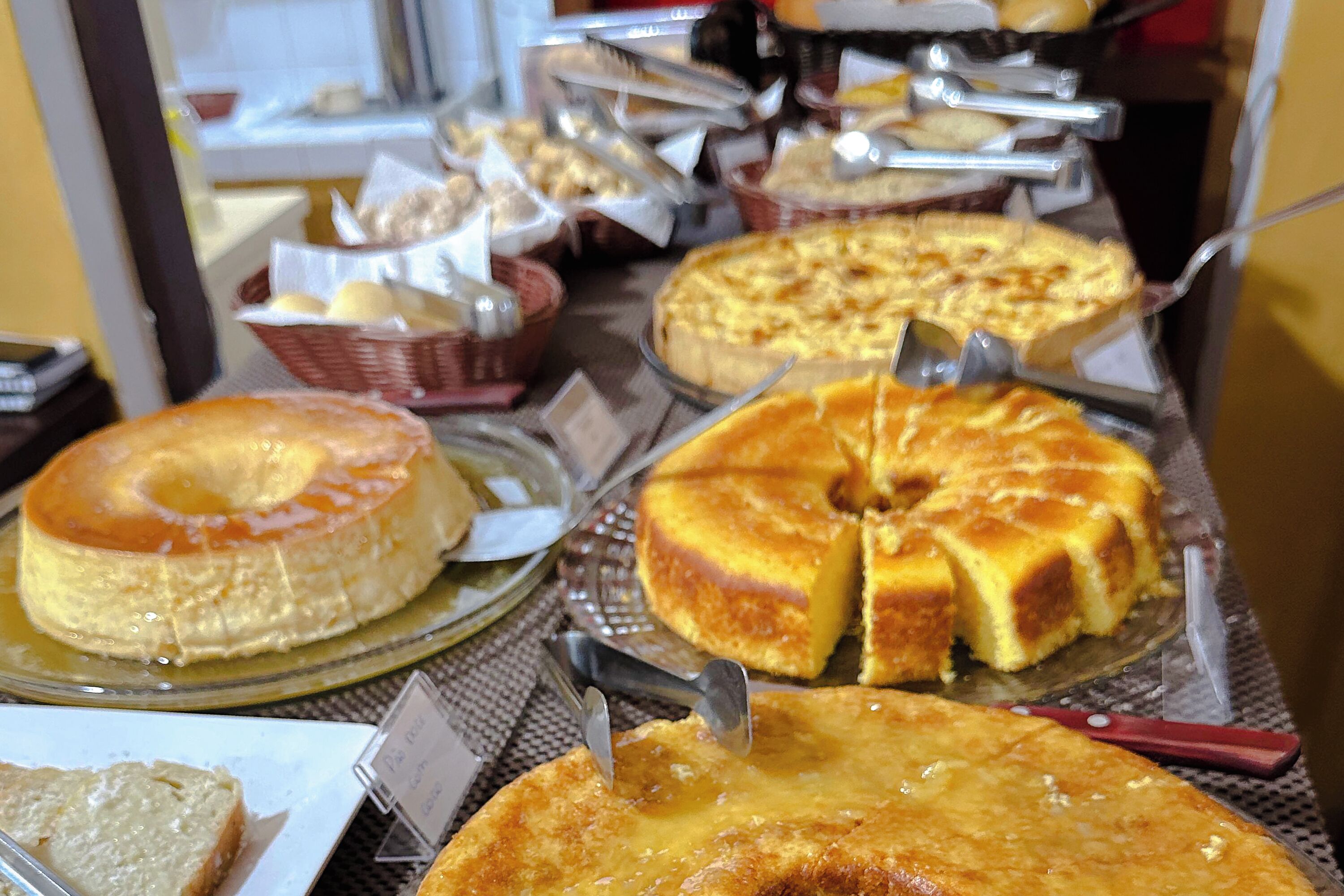Buffet com diversos bolos e doces dispostos em bandejas.