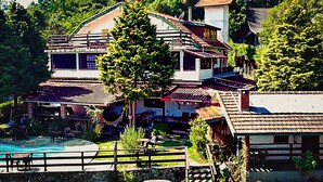 Ein zweistöckiges Haus mit Swimmingpool, umgeben von üppiger Vegetation.