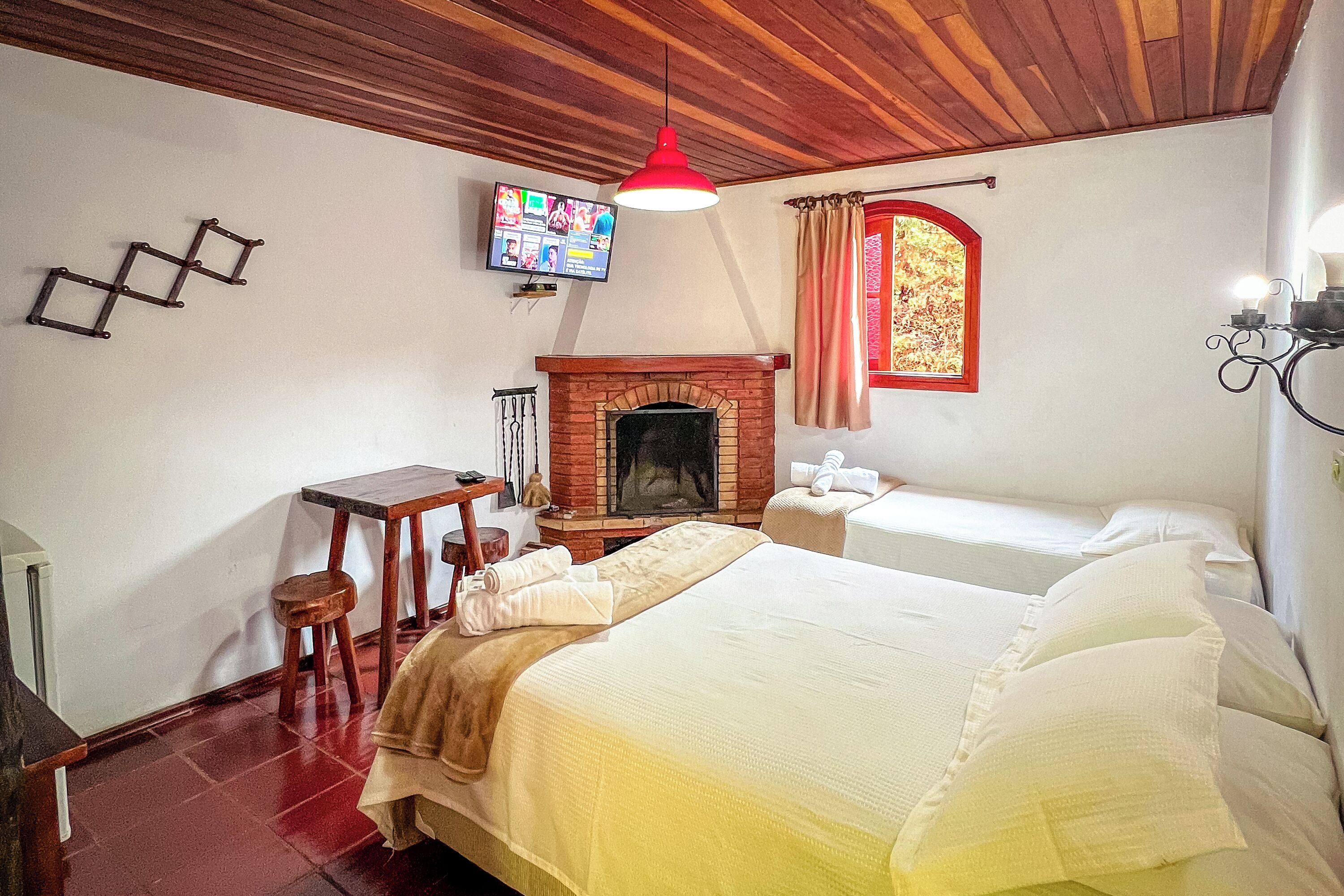 Una habitación acogedora con una cama, una mesita, un televisor y una chimenea.