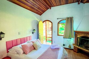 Un dormitorio con cama, chimenea y vistas al exterior.