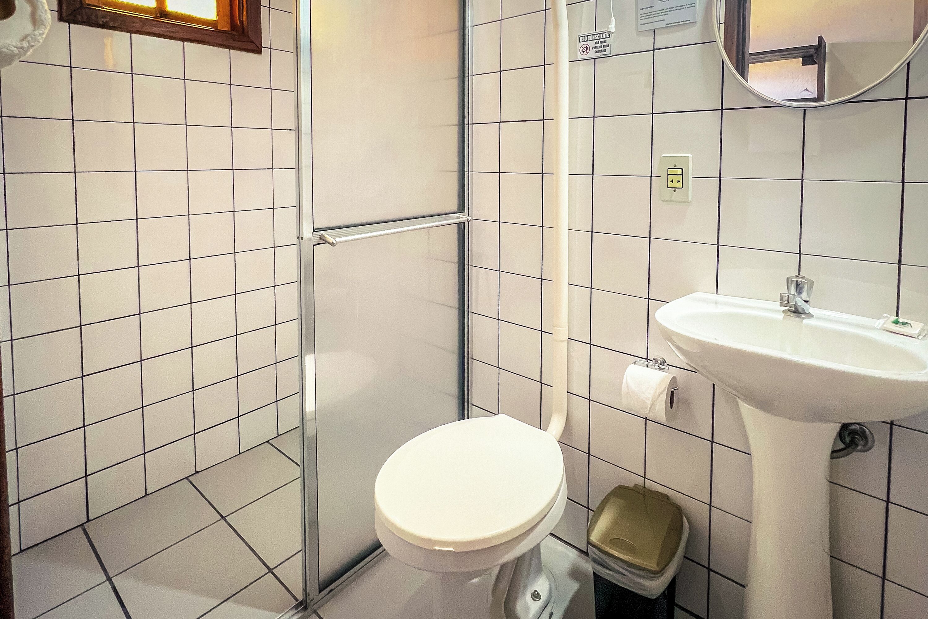 A bathroom with a toilet, sink, and a trash bin.