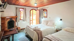 Ein Zimmer mit zwei Betten, einem Kamin und einem an der Wand befestigten Fernseher.