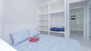 Una camera da letto con un letto, un armadio e un bagno parzialmente visibile attraverso una porta aperta.