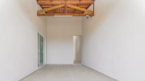 Un'ampia stanza vuota con soffitto alto e travi in legno a vista.