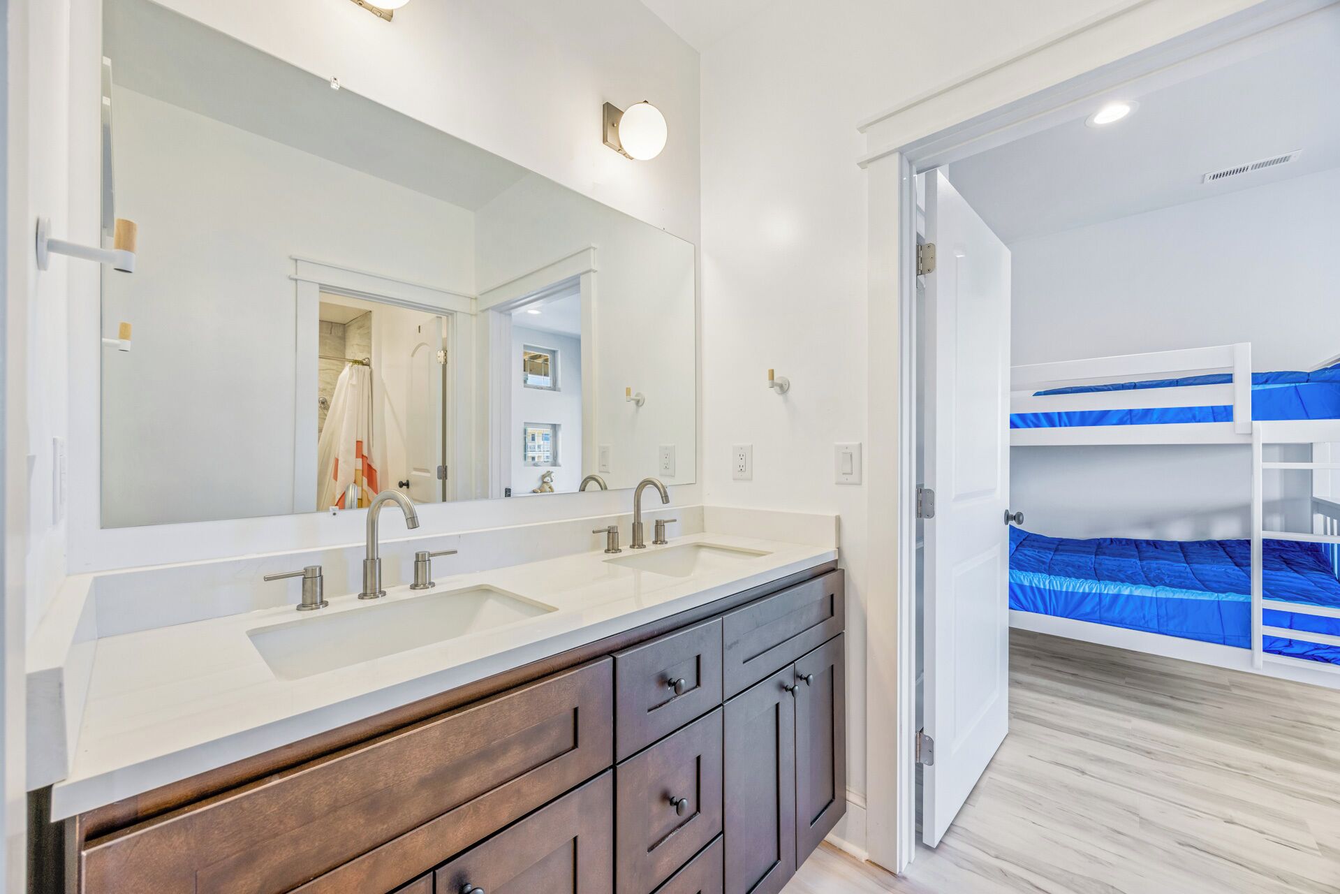 A bathroom with a double sink, a large mirror, and a wooden vanity.