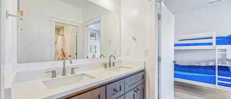 A bathroom with a double sink, a large mirror, and a wooden vanity.