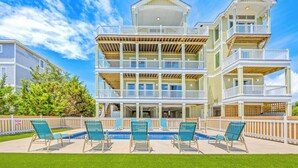 A multi-story building with balconies, a swimming pool, and outdoor seating. - New Soundside Dog Friendly Avon Retreat with Pool, Hot Tub, Game Room, Theater (Salvo)