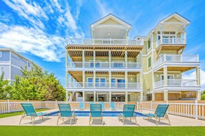 A multi-story building with balconies, a swimming pool, and outdoor seating. - New Soundside Dog Friendly Avon Retreat with Pool, Hot Tub, Game Room, Theater (Salvo)