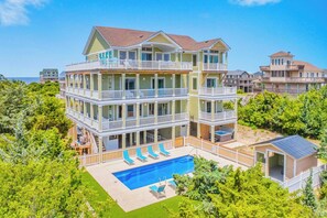 A multi-story beachfront property with a swimming pool, balconies, and a view of the ocean. - New Soundside Dog Friendly Avon Retreat with Pool, Hot Tub, Game Room, Theater (Salvo)