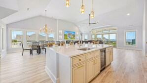 A spacious kitchen with a large island, pendant lighting, and a view of the ocean. - New Soundside Dog Friendly Avon Retreat with Pool, Hot Tub, Game Room, Theater (Salvo)