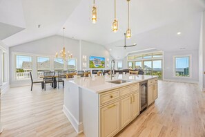 A spacious kitchen with a large island, pendant lighting, and a view of the ocean. - New Soundside Dog Friendly Avon Retreat with Pool, Hot Tub, Game Room, Theater (Salvo)