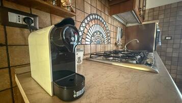 A kitchen with a coffee maker, a stove, and a decorative backsplash.