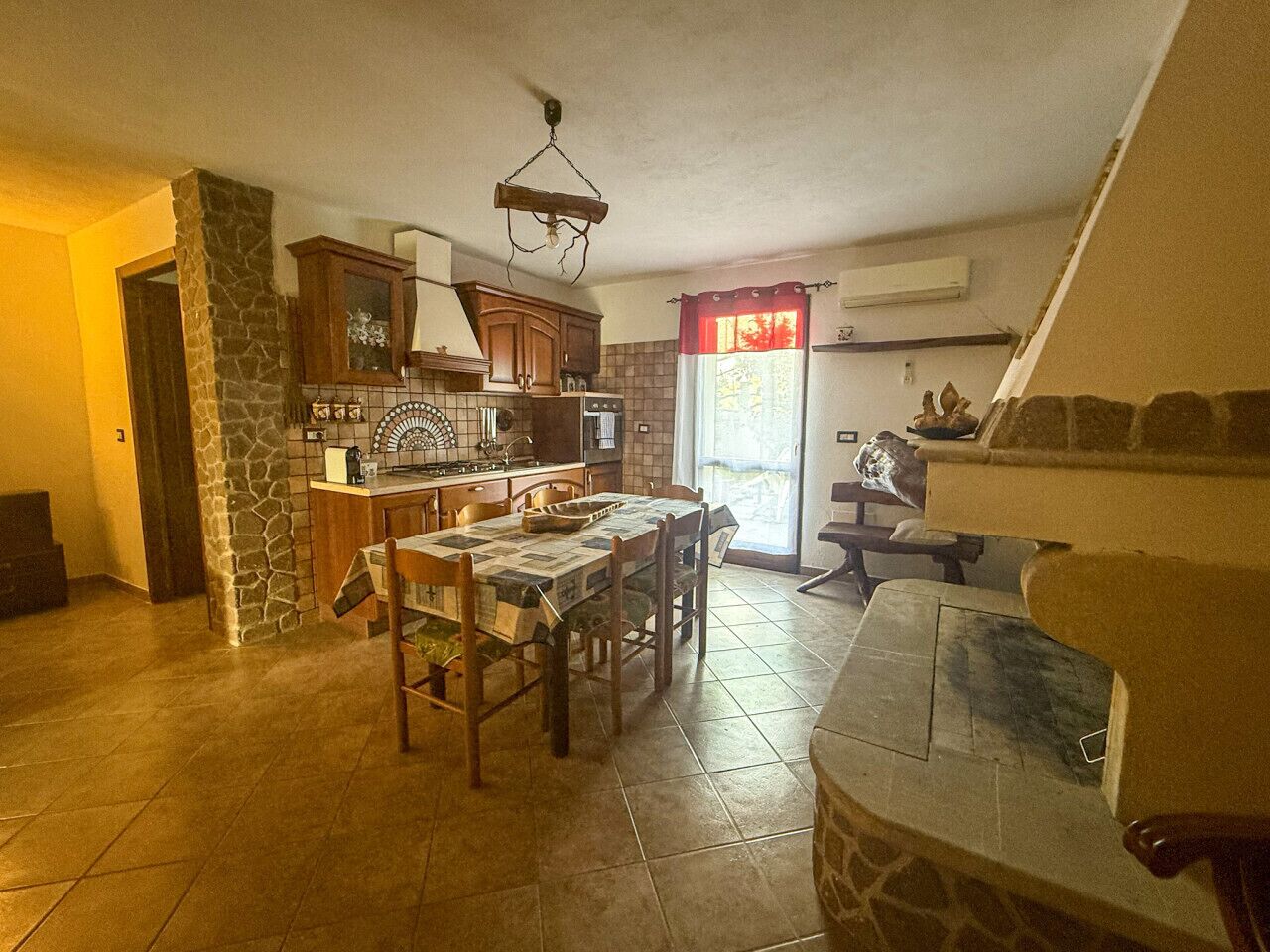 A spacious kitchen with a dining table, stone pillar, and wooden cabinets.