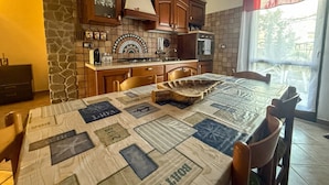 A kitchen with wooden cabinets, a tiled backsplash, and a dining table with a quilted tablecloth. - L`ulivo - Portoscuso (Portoscuso)