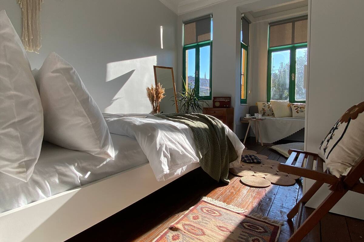 Een gezellige slaapkamer met een bed, een houten vloer, een kamerkleed met dessin en een hanglamp.