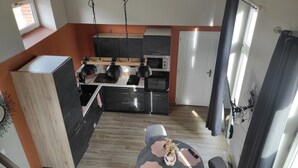 A modern kitchen with a central island, a dining area with a round table, and a view of the living room.