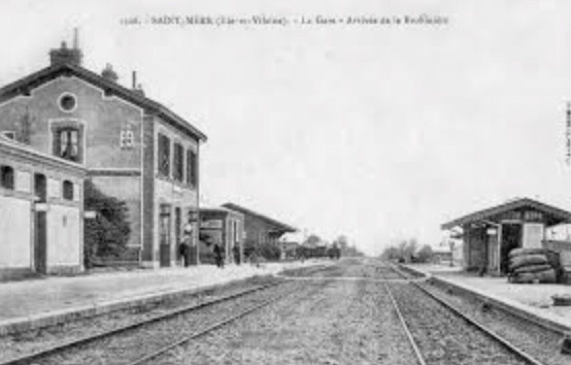 A historical train station with a single-story building, a platform, and a railway track.