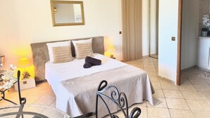 A bedroom with a bed, bedside lamps, a mirror, and a hanging light fixture. - Villa baie des anges (Nice)