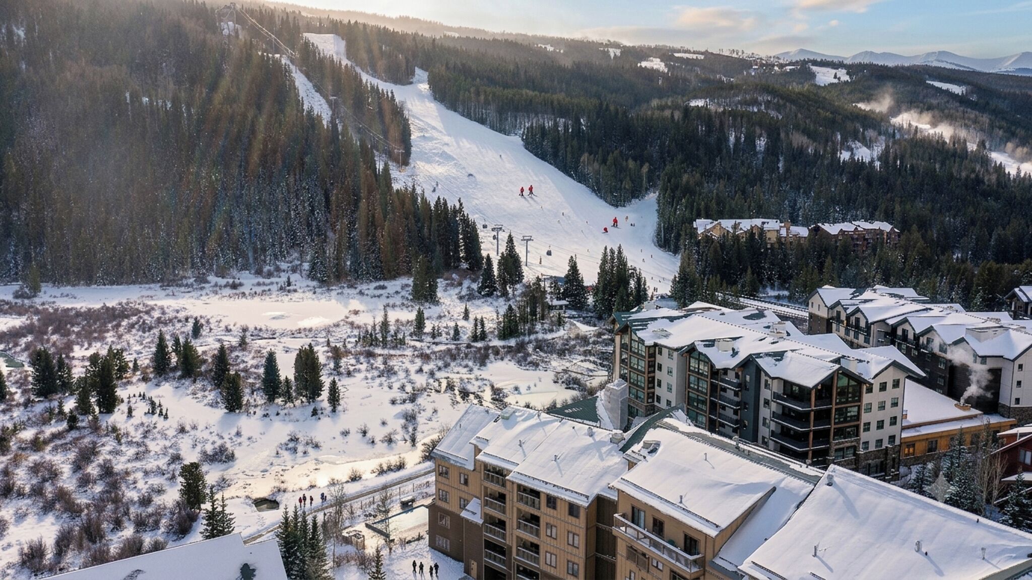 Ein Skigebiet mit schneebedeckten Pisten, Gebäuden mit Balkonen und einer Bergkulisse.