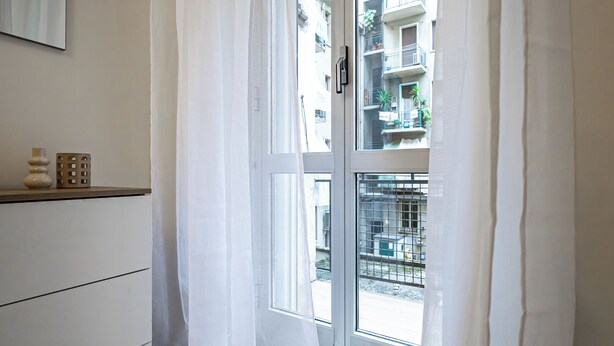 A room with a window, a white door, and a shelf with decorative items. - Italianway Comfort - Sammartini 35 (Milan)