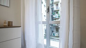 A room with a window, a white door, and a shelf with decorative items. - Italianway Comfort - Sammartini 35 (Milan)