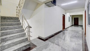 A clean, well-lit hallway with marble flooring, a staircase with metal railings, and a ceiling-mounted air conditioning unit. - Super Collection O Sathyabama University (Chennai)