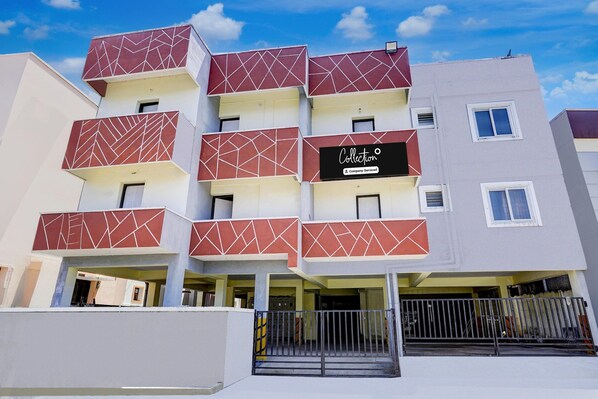 A multi-story building with a geometric facade design, a visible company sign, and a gated entrance. - Super Collection O Sathyabama University (Chennai)